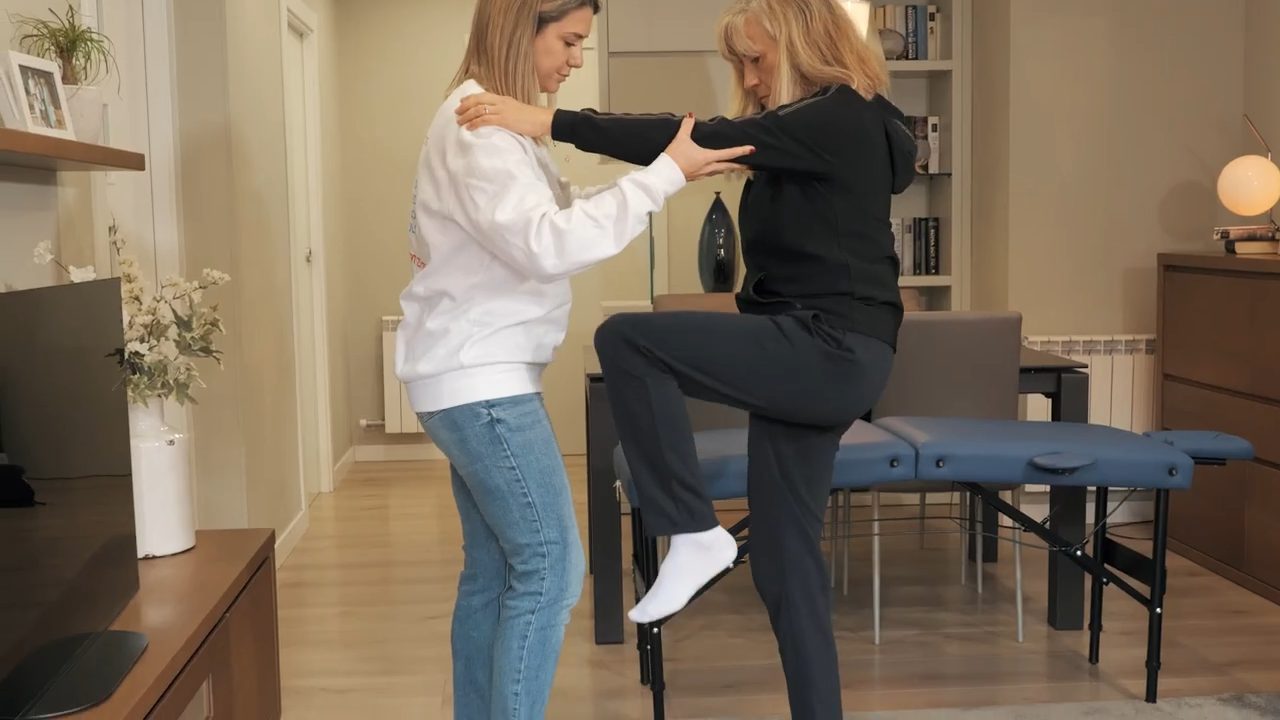 Persona mayor realizando ejercicios de rehabilitación geriátrica con una fisioterapeuta en su domicilio en Barcelona