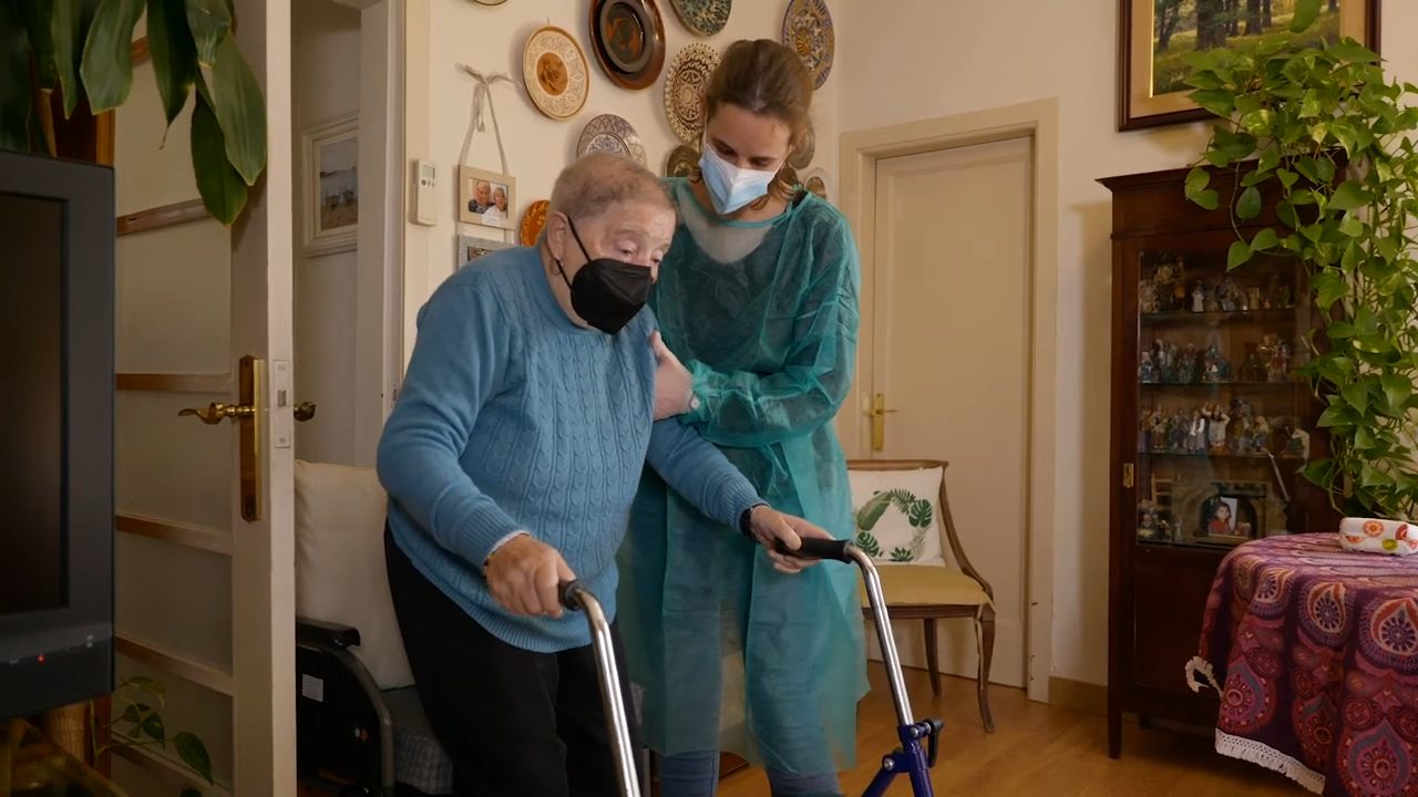 Fisioterapeuta ayudando a un paciente con ejercicios de rehabilitación neurológica en su casa