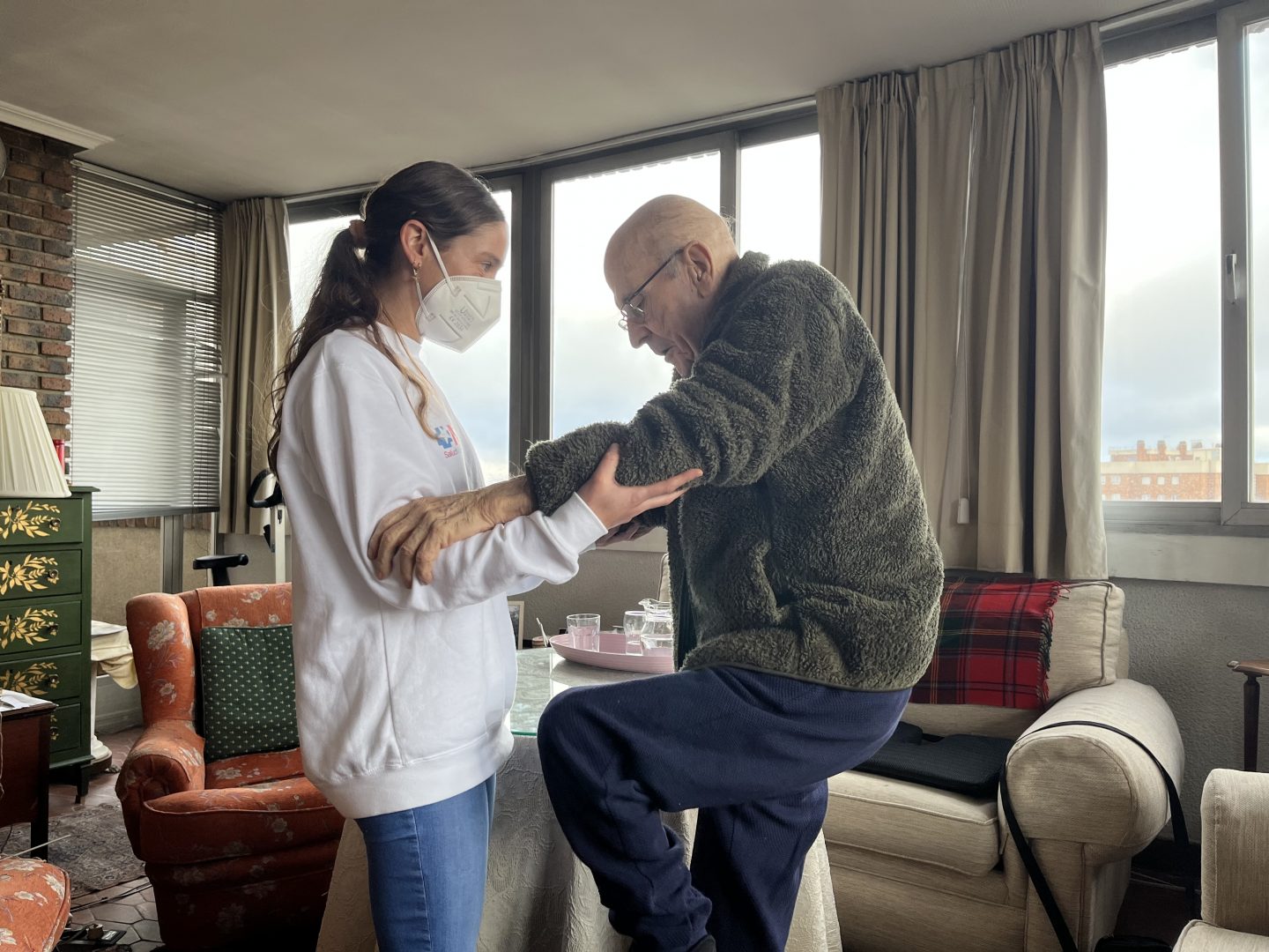Fisioterapeuta trabajando con una persona mayor en su domicilio en Barcelona.
