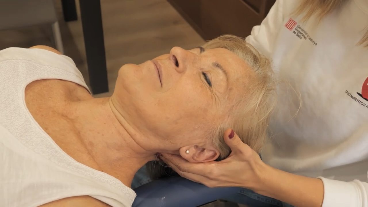 Fisioterapeuta realizando un masaje terapéutico a una persona mayor en su casa.